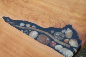 Художники заполняют трещины в столах ракушками, камешками и морскими звёздами