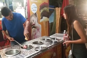 Весёлый продавец мороженого отдает девушке заказанный рожок