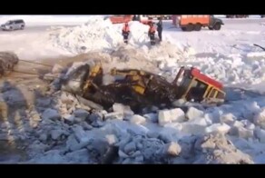 Бульдозер вытягивают из воды зимой