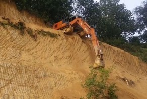 Машинист экскаватора спускает свою машину с обрывистого холма