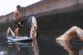 Художник рисует потрясающие картины у воды, стоя на доске для серфинга