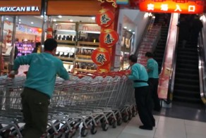 Сотрудники китайского супермаркета поднимают тележки на эскалаторе