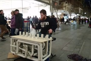 Уличный музыкант играет на канализационных трубах