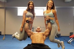 Тяжелоатлет качает мышцы рук, используя девушек в качестве гантелей