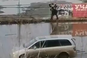 В Омске огромная лужа заставила девушку лезть по забору