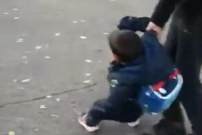 Первоклассник пытается вырваться из рук отца, потому что не хочет идти в школу