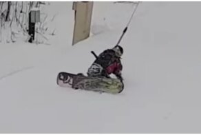 Начинающий сноубордист пытается справиться с бугельным подъемником