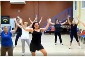 Женщина пытается успеть за коллективом во время фитнес тренировки