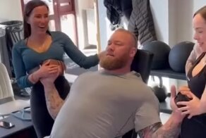 Силач упражняется с двумя миниатюрными женщинами