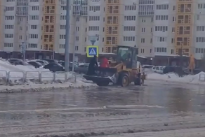 Работяга на экскаваторе помогает людям перейти дорогу, которая превратилась в одну большую лужу