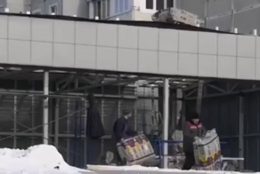 Рабочие  пытаются закинуть утеплитель на крышу