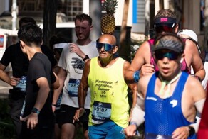 Пожилой мужчина бегает марафоны, удерживая ананас на голове