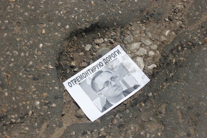  В Кимрах дыры на дорогах заделали портретами мэра с его цитатами