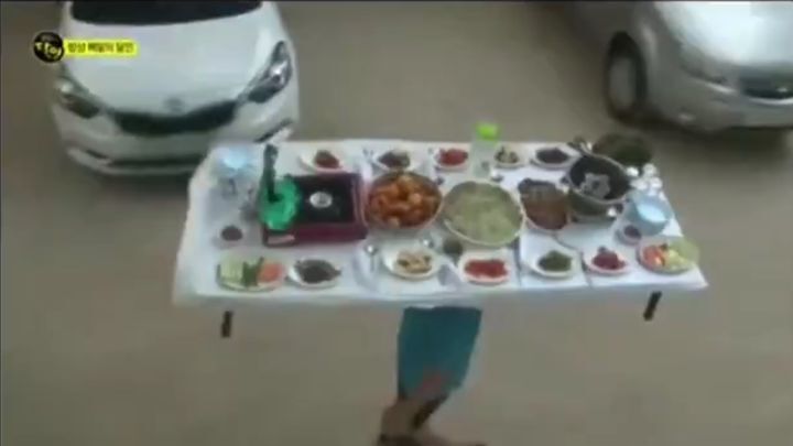 Корейский официант носит на голове обеденный стол, заставленный блюдами