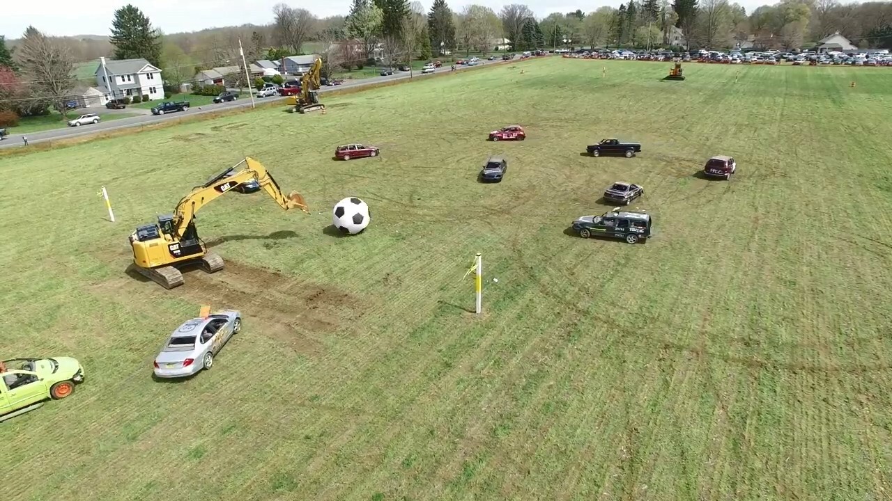 Автомобили с экскаватором играют в футбол