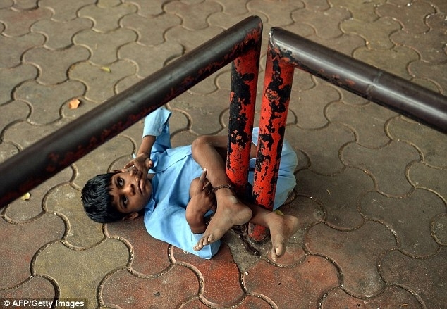 Индийская бабушка привязывает своего внука за ноги к остановке
