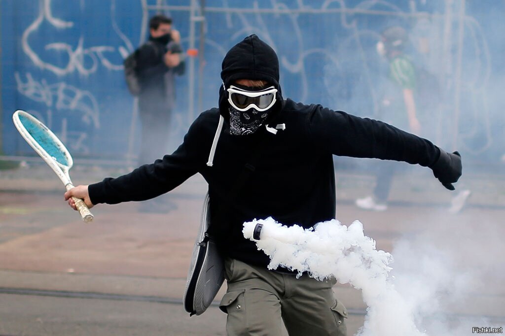 Протестующий использыет ракетку чтобы отбить гранату со слезоточивым газом во...
