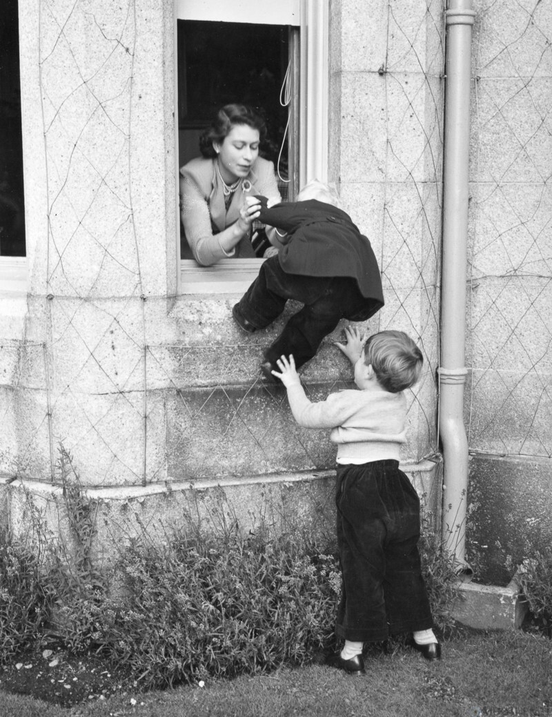 28 сентября 1952: Королева Елизавета затаскивает маленького принца Чарльза в окно