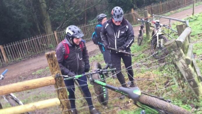 Трое мужчин пытаются вытащить велосипед, застрявший в электрическом заборе