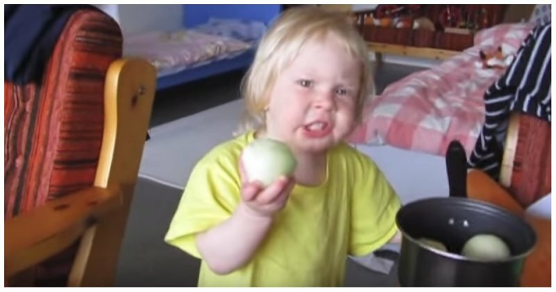 Девочка с нордическим характером пытается есть луковицу как яблоко