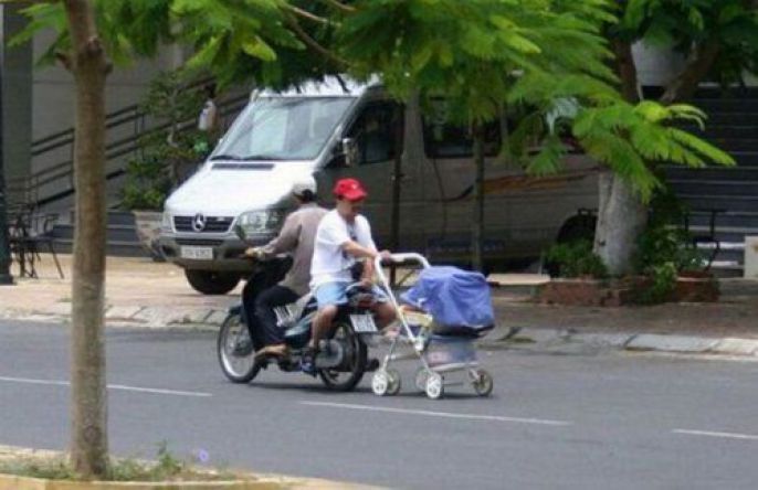 Backwards on a motorcycle holding a baby 