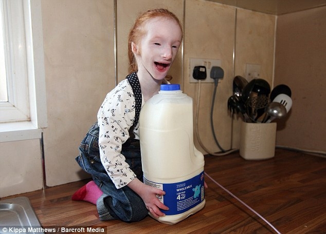 Worlds Smallest Girl Sitting next to gallon of milk 