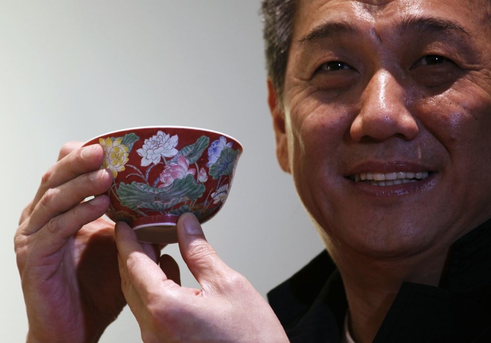 Hong Kong Chinese ceramics dealer William Chak poses with a magnificent Ruby-Ground Falangcai "Double-Lotus" Bowl