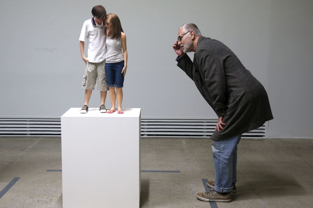 A visitor looks at a sculpture entitled "Young Couple, 2013"