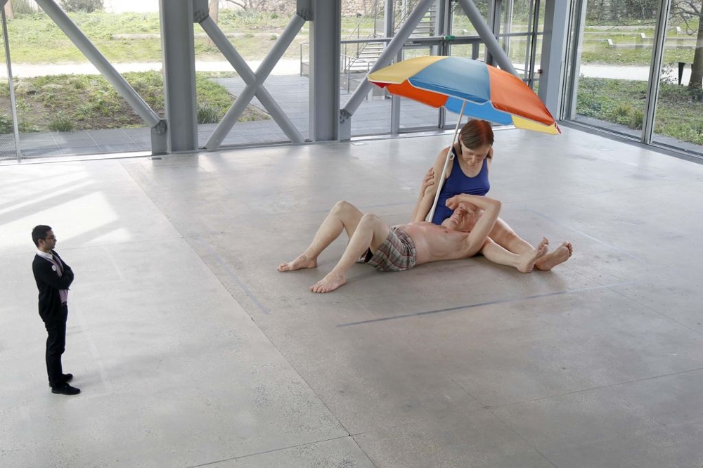 An employee looks at a sculpture entitled "Couple Under an Umbrella, 2013"