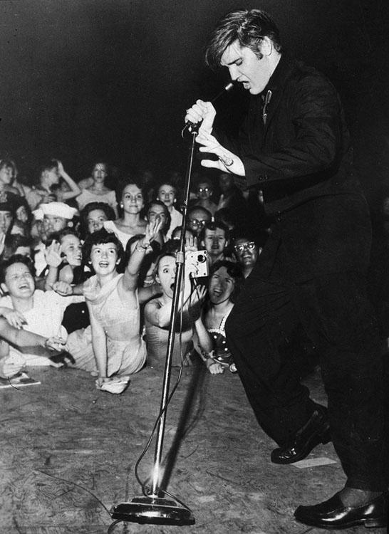 Borsi standing in the front row with her cell phone camera pointed at Presley 