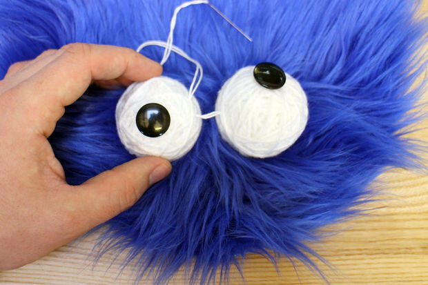 He attached black buttons for the pupils and then sewed the eyes onto the head.