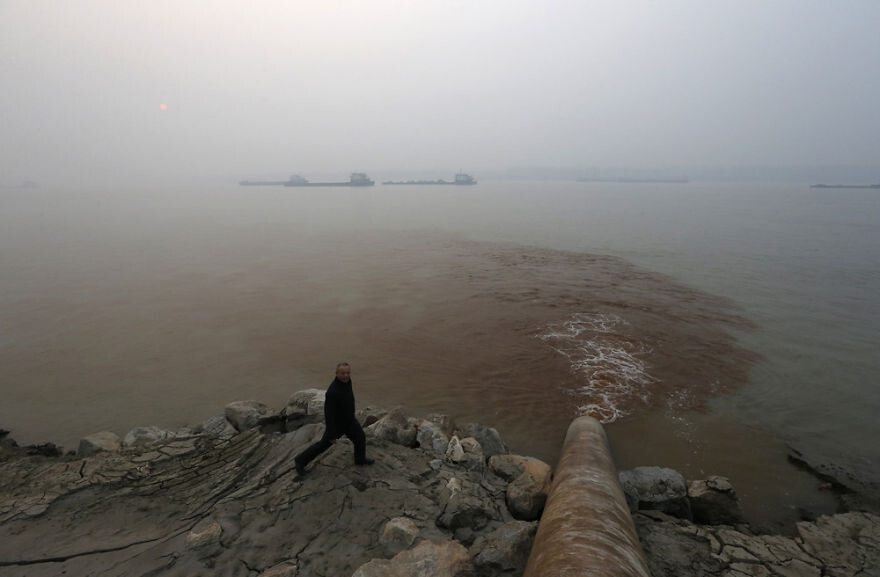 Man Walks By Pipe Discharging Waste Water Into Yangtze River