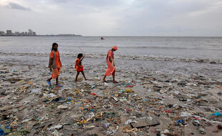 A Family Walks On A Garbage-strewn Beach In Mumbai