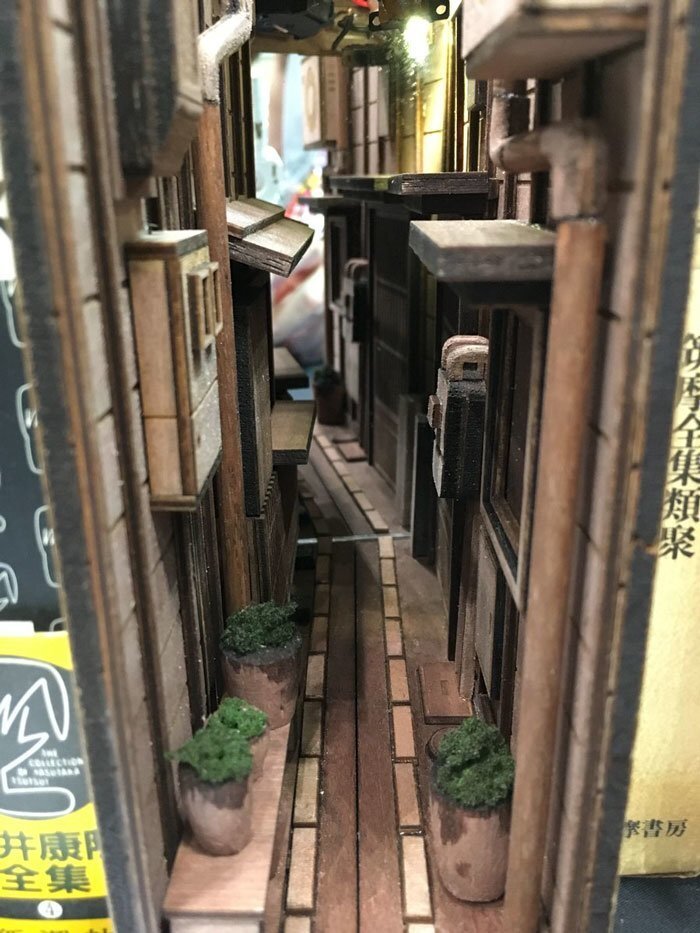 The wooden model is sized to fit snuggly between two paperback novels and even includes lights to add to the aesthetic of dimly lit back alley.