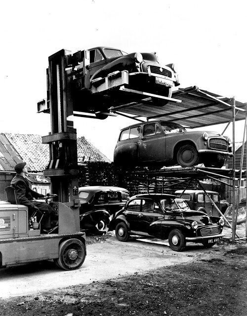 A man parks a car with the help of a forklift, ca. 1955.