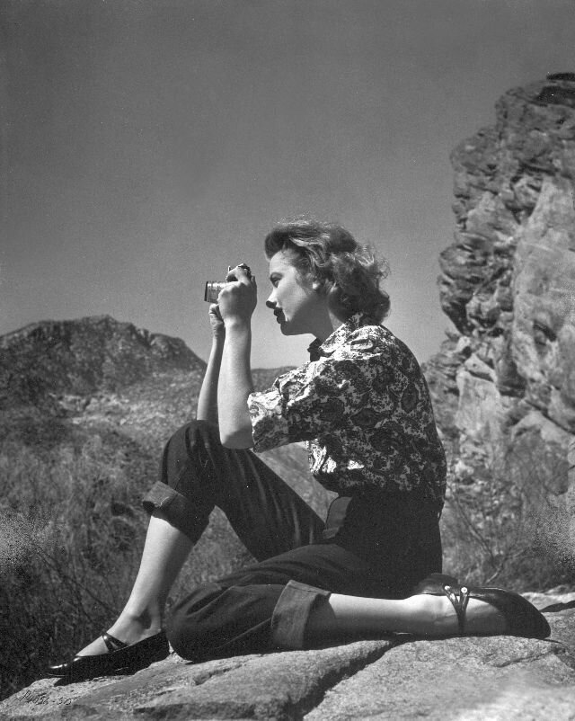 1951. Kelly snaps a photo on a rock while on a hiking trip.