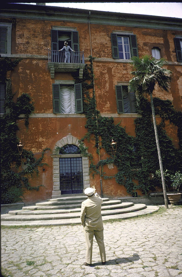 Sophia Loren standing on balcony of her study talking to Carlo Ponti who is standing in the garden below.