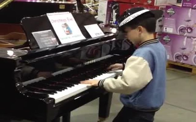 Одаренный ребенок играет на рояле в магазине 