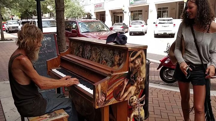 Бездомный мужчина талантливо играет на пианино на улице 