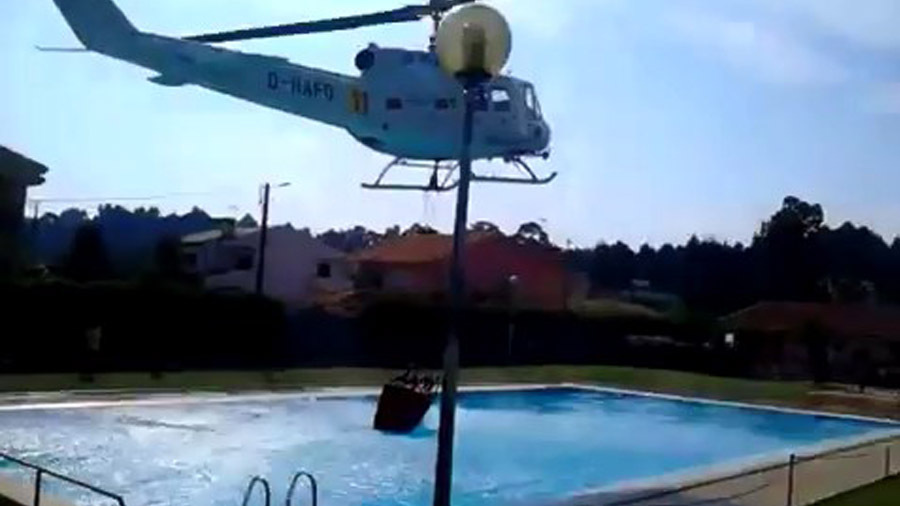 Пожарный вертолет берет воду из бассейна 