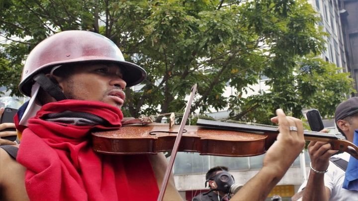 Протестующий играет на скрипке на митинге в Венесуэле  