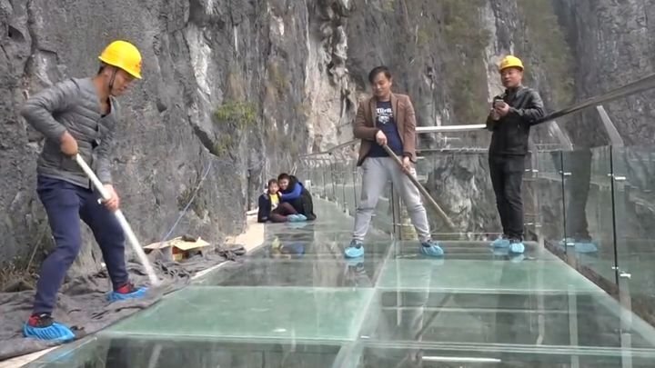 Рабочие с помощью кувалд испытывают на прочность новый стеклянный мост в горах Китая 