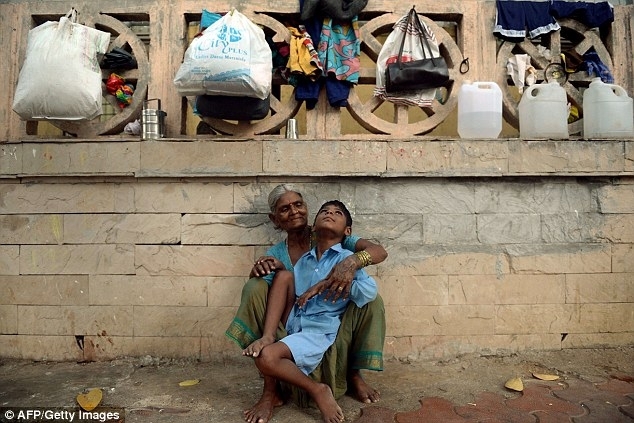 Индийская бабушка привязывает своего внука за ноги к остановке
