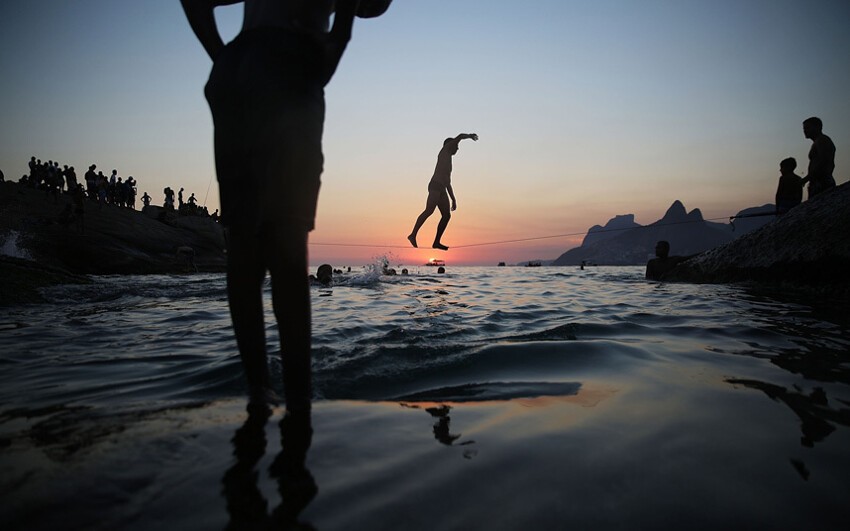 Занятия слэклайном на скалистом пляже Арпоадор в Рио-де-Жанейро, Бразилия.