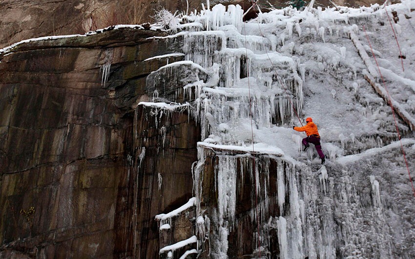 Альпинист поднимается по оледеневшей стене в городе Либерец, Чехия. 