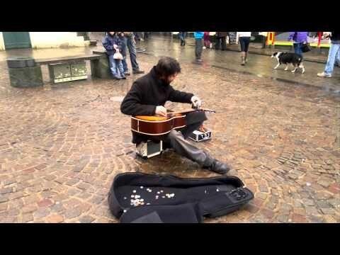Уличный музыкант играет на гитаре флягой для алкоголя 