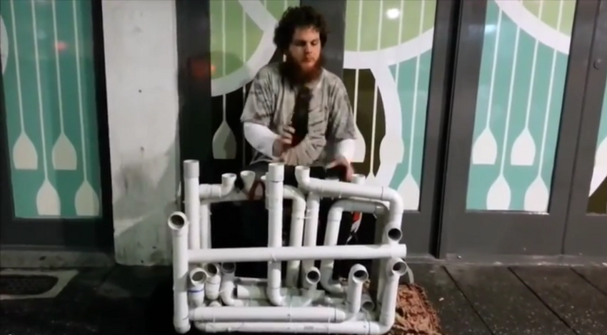 Уличный музыкант играет на водопроводных трубах 