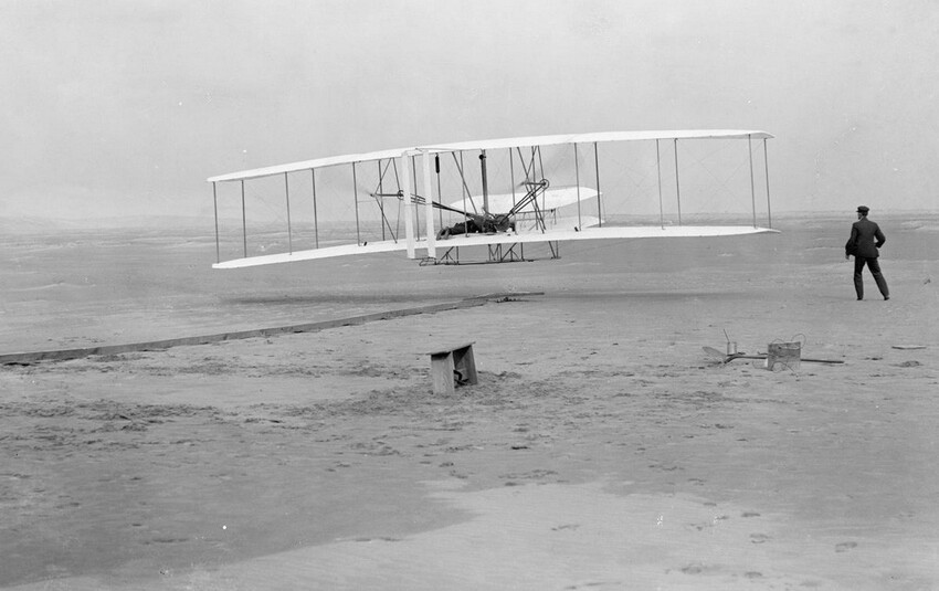 10. Первый полет: 120 футов в 12 секунд, 17 декабря 1903 года. Орвилл Райт за штурвалом машины. Уилбур Райт бежит рядом, чтобы сбалансировать машину.