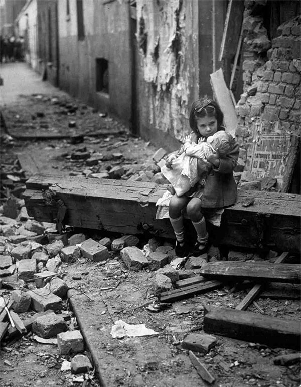 2, Английская девочка, держащая куклу, сидит на развалинах своего разрушенного при бомбёжке дома. 1940 год.
