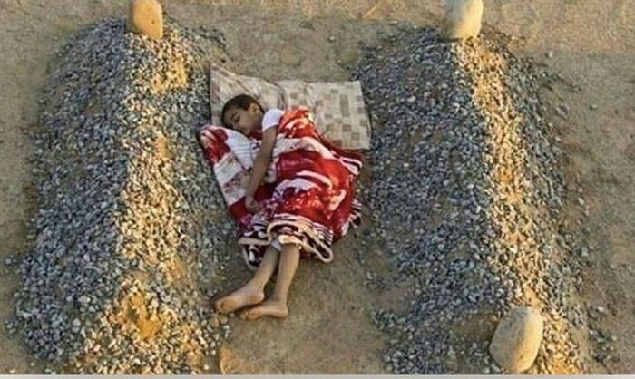 Сирийский мальчик спит между могилами родителей 